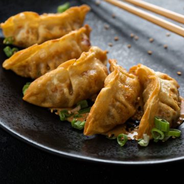 ling ling potstickers on black plate with chopped scallion